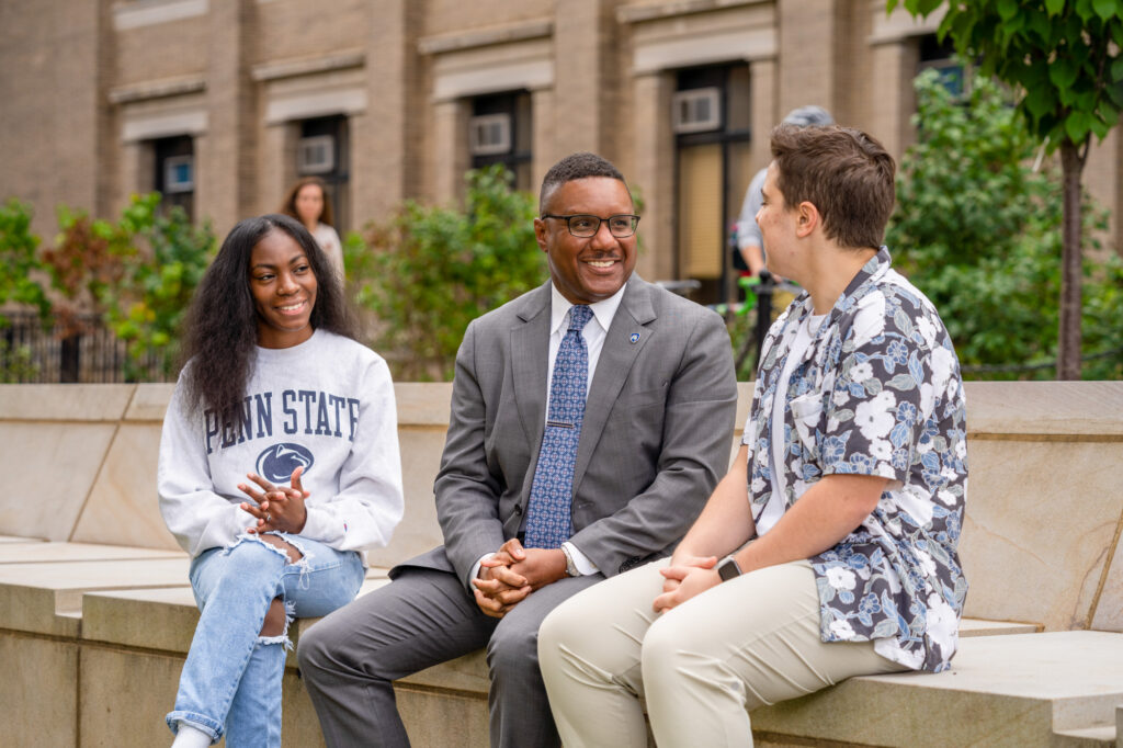 Dean Clarence Lang (center) sits outside Sparks Building with students Janiyah Davis (left) and Carter Gangl (right).