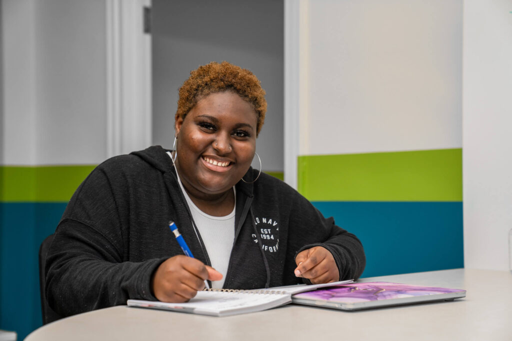 Student Bineta Brooks smiles while doing homework in the Chaiken Center for Student Success.
