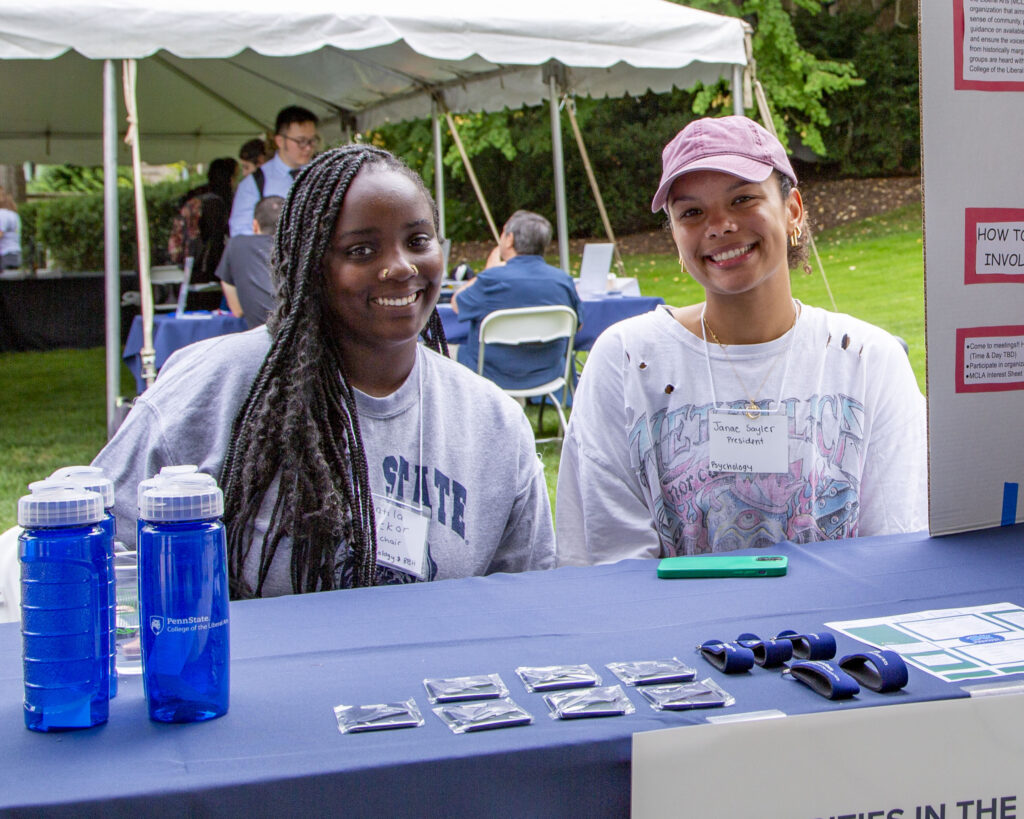 Matila Sackor and Janae Sayler, two Liberal Arts students, sit behind the Minorities in the College of the Liberal Arts table at the Liberal Arts Undergraduate Festival in September 2022.