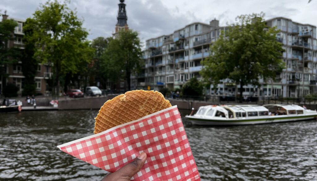 Simone Miller holds a waffle with the city view of Amsterdam, Netherlands in the background.