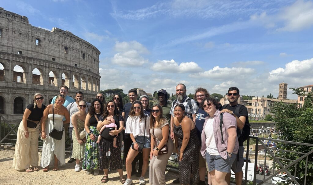 Students on the summer 2023 faculty-led course trip to Rome, Italy standing outside with the Colosseum in the background.