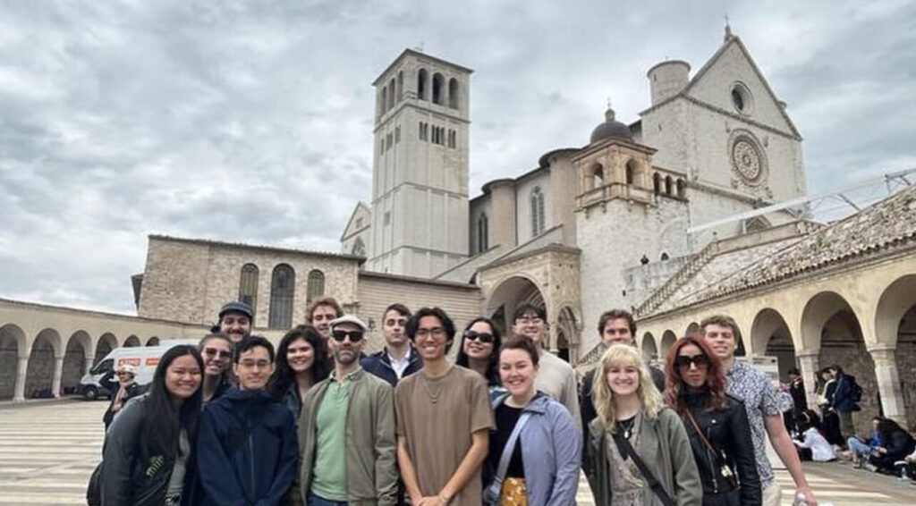 A group of people stand in front of an Italian building.