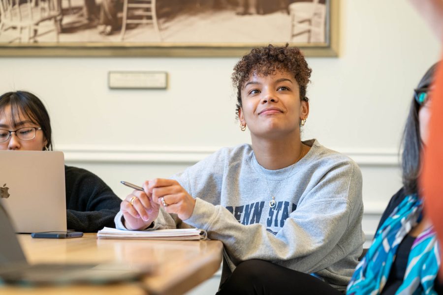 Janae Sayler, a 2023 Liberal Arts alumna, smiling and sitting at a desk in a classroom.
