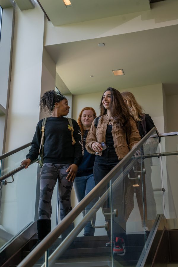 Four Liberal Arts students walk down steps in Burrowes Building while conversing.