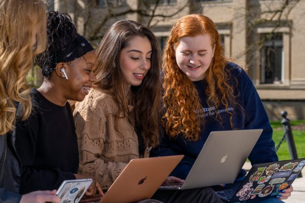 Three Liberal Arts students look at their laptops while sitting on Pattee Mall.