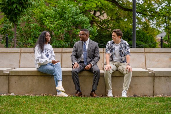 Students Janiyah Davis (left) and Carter Gangl (right) sit with Dean Lang (center) outside Sparks Building.