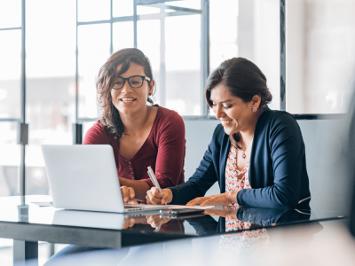 Two employees sit behind a laptop at work