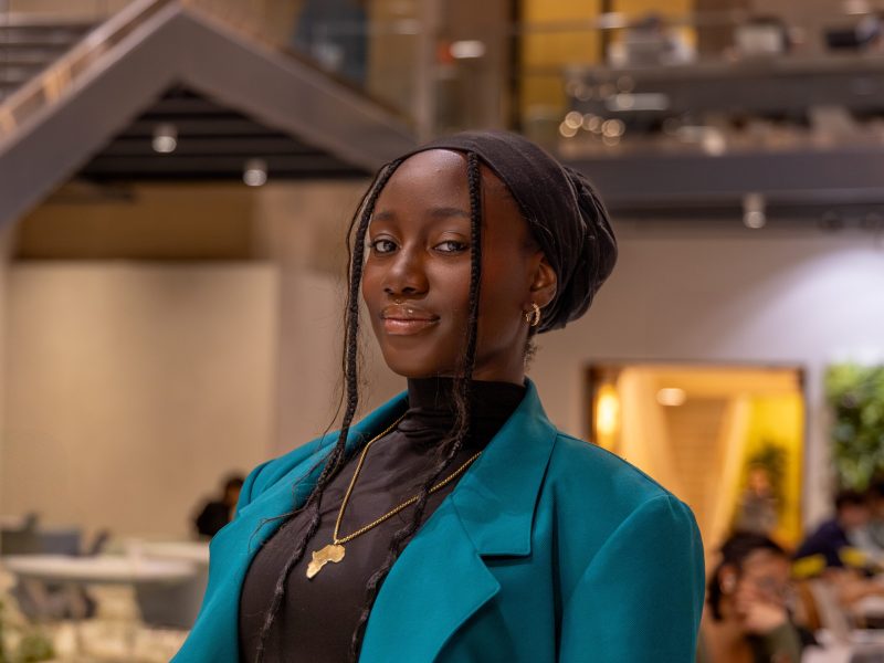 Cherish Graham, who will graduate Penn State in 2026, wears a turquoise jacket and gold necklace with a continent of Africa pendant.