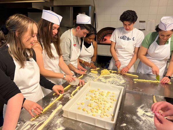 A group of students surround a table, learning to make homemade gnocchi.