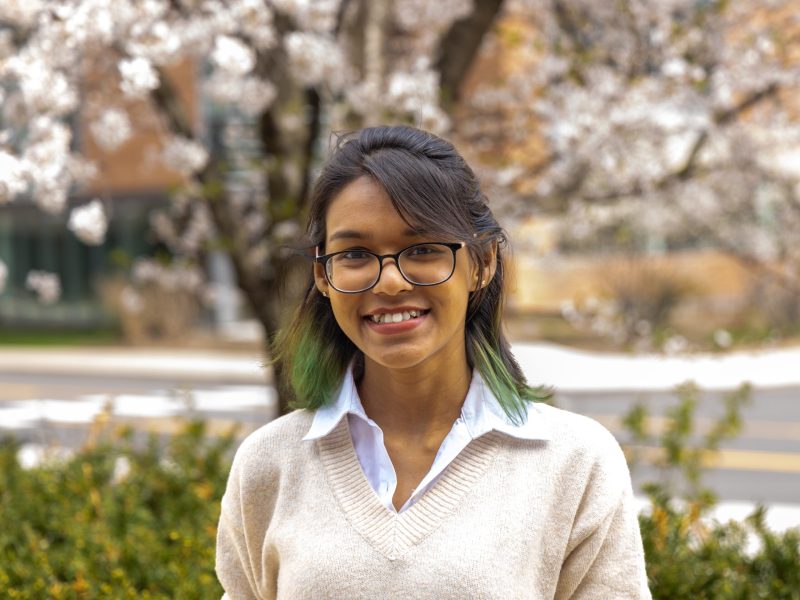 Halima Binte Islam Halima Binte Islam, outdoors while smiling in glasses, a tinge of green in her hair and white sweater with white a collared shirt underneath.