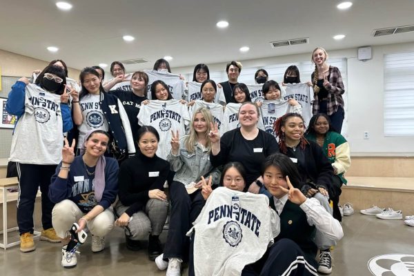 Penn State KOR 499 students interacting with female Korean high schoolers and exchanging Penn State shirts as gifts.