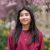 Jedily Alvarado, who will graduate from Penn State in 2026, stands before a blossoming tree wearing a red sweatshirt.