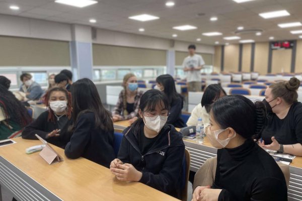 Penn State KOR 499 students interacting with female Korean high schoolers and exchanging Penn State shirts as gifts.