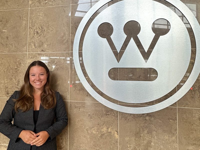 Sabrina Knox, who will graduate from Penn State in 2026, stands next to the Westinghouse logo inside a Westinghouse building in Pittsburgh.