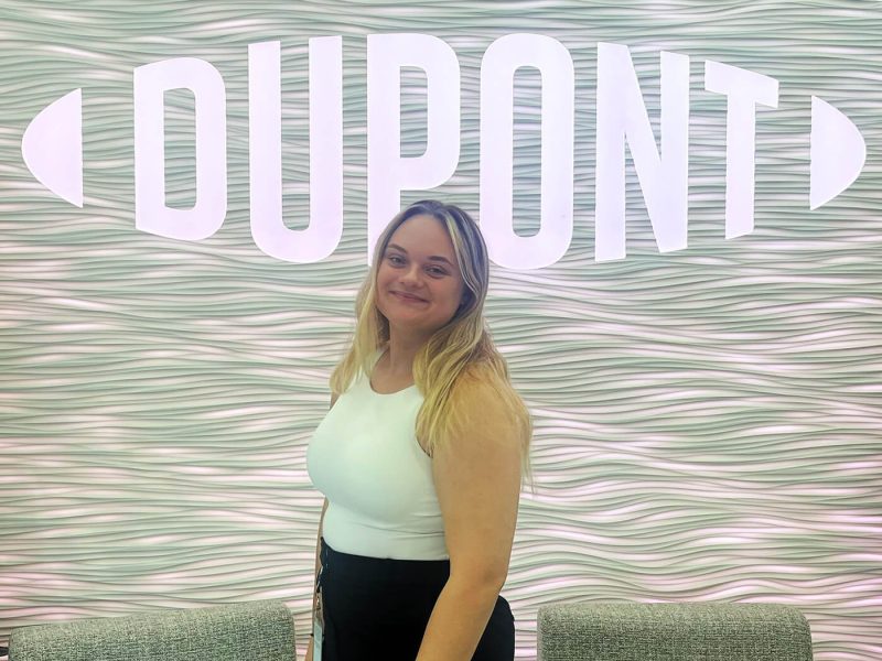 Penn State student, Paris Pavelchik stands in front of the DuPont logo at their office in Midland, Michigan.