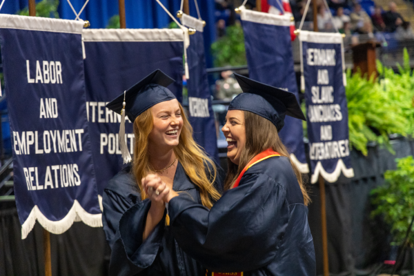 Two students in academic regalia celebrate during their commencement ceremony.