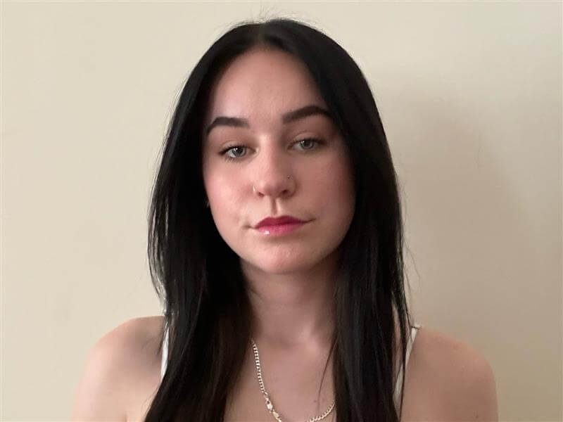 Sarah Stein, who will graduate from Penn State in 2025, poses for a headshot in front of an ivory wall.