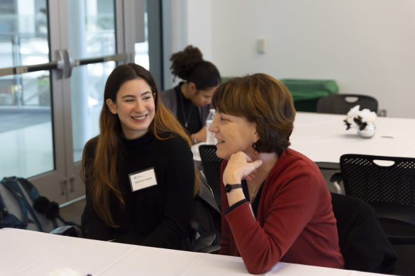 A student and an alumnus sit at a table and talk.