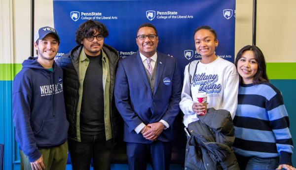 Four Liberal Arts students pose with Dean Lang (center) in front of a College of the Liberal Arts backdrop in the Chaiken Center during the Liberal Arts First-Gen Celebration on November 8, 2022.